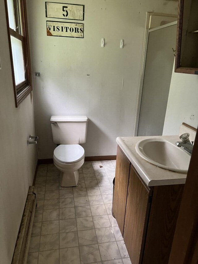 bathroom featuring vanity, baseboard heating, a shower with shower door, and toilet