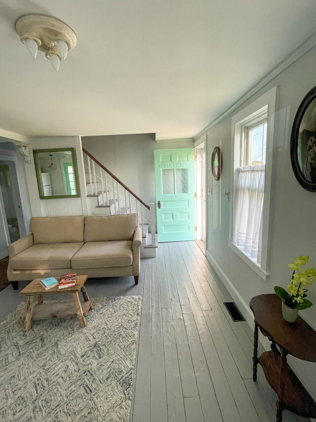 living area with stairway, baseboards, visible vents, and wood finished floors