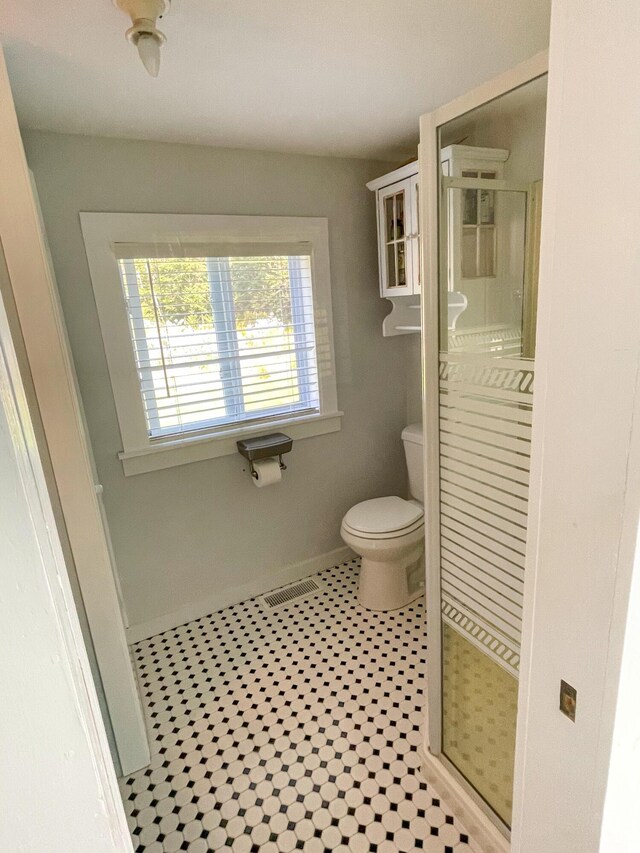 bathroom featuring tile patterned flooring, toilet, and an enclosed shower