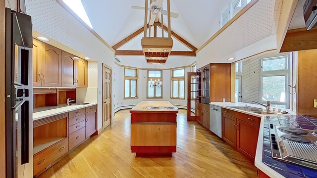 kitchen with a center island, light hardwood / wood-style flooring, stainless steel appliances, sink, and high vaulted ceiling