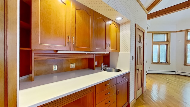 kitchen with light wood-type flooring, vaulted ceiling, a baseboard heating unit, and sink