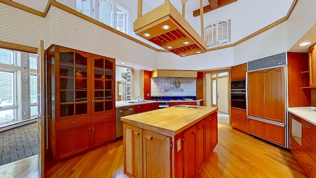 kitchen featuring a high ceiling, built in appliances, a center island, and butcher block counters