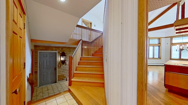 stairway featuring a baseboard heating unit, high vaulted ceiling, wood-type flooring, and a notable chandelier