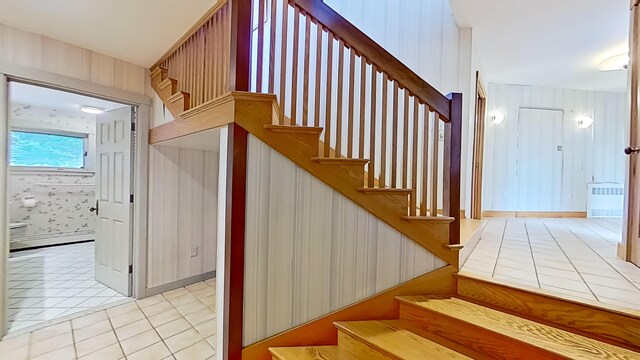 stairway with a baseboard radiator and tile patterned flooring