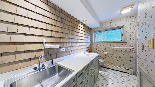 interior space with a baseboard heating unit, gray cabinetry, sink, and light tile patterned flooring