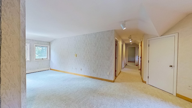 carpeted empty room featuring vaulted ceiling and baseboard heating