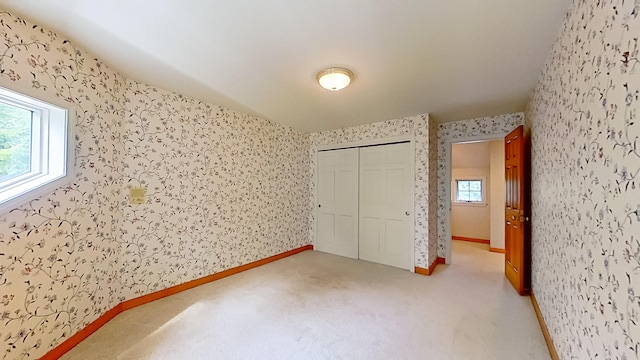 unfurnished bedroom with carpet, a closet, and multiple windows