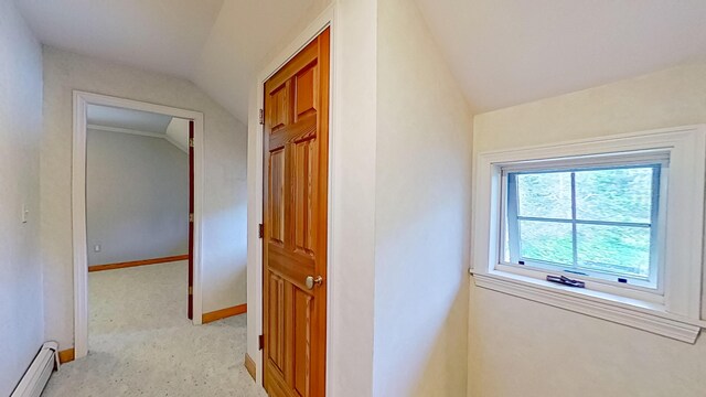 corridor with lofted ceiling, a baseboard radiator, and light colored carpet