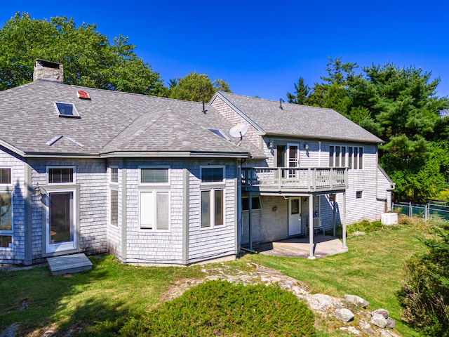 rear view of house with a yard, a wooden deck, and a patio