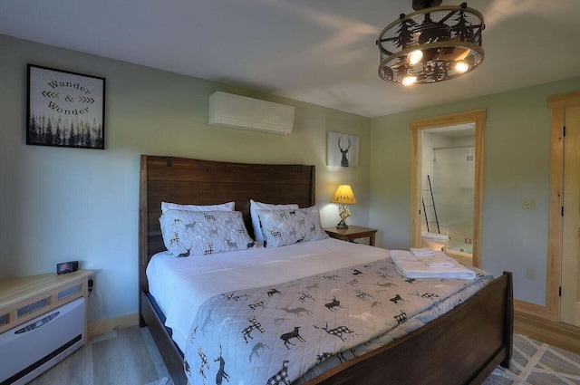 bedroom with a wall mounted AC, wood-type flooring, and ensuite bath