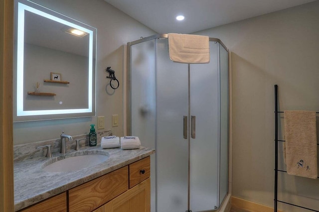 bathroom featuring a shower with door and vanity