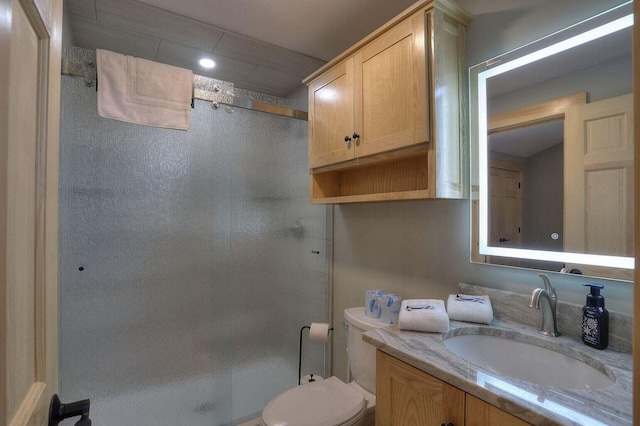 bathroom with toilet, a shower with door, and vanity