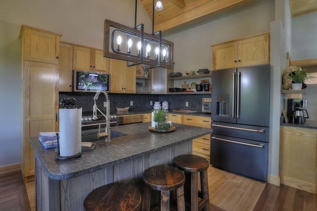 kitchen featuring lofted ceiling with beams, appliances with stainless steel finishes, pendant lighting, and light hardwood / wood-style floors