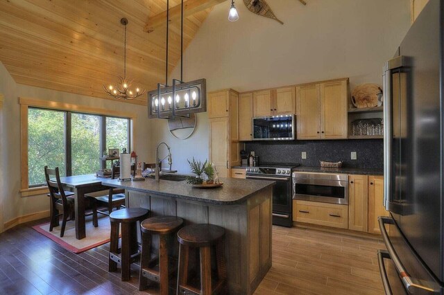 kitchen with stainless steel appliances, sink, light wood-type flooring, and an inviting chandelier