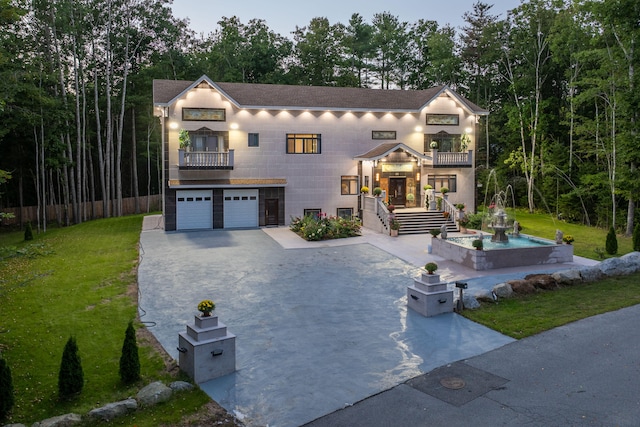 view of front of house featuring a balcony, a garage, and a yard