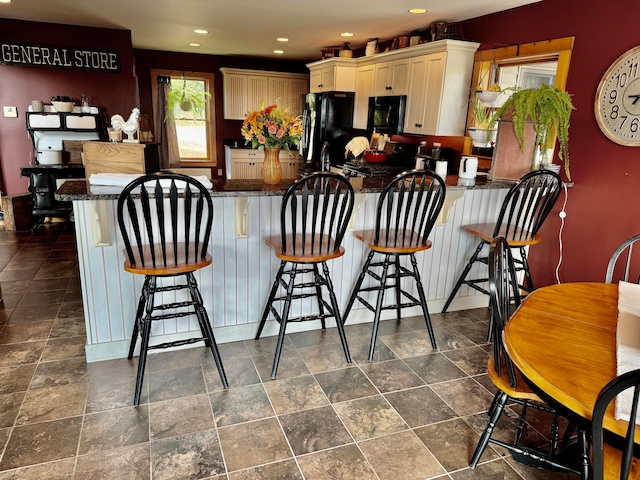 kitchen with sink, black refrigerator, kitchen peninsula, and a kitchen breakfast bar