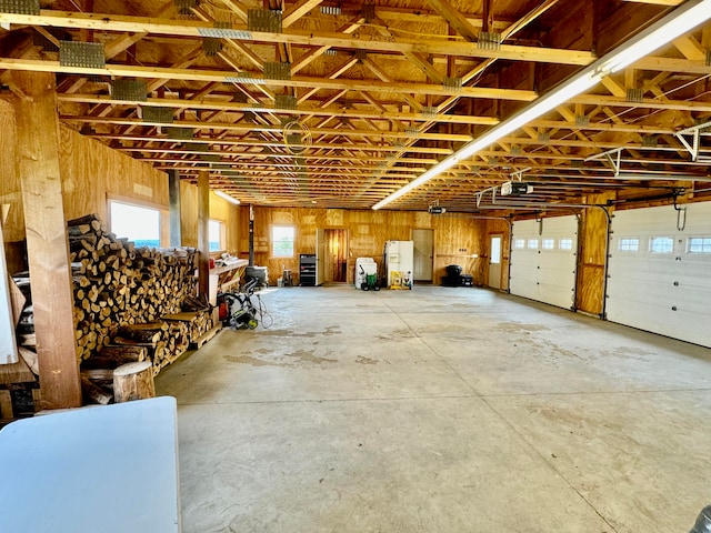 garage with a garage door opener, white fridge, and wooden walls