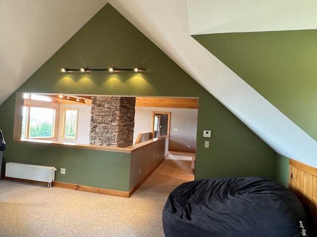 carpeted bedroom featuring rail lighting, radiator heating unit, and vaulted ceiling