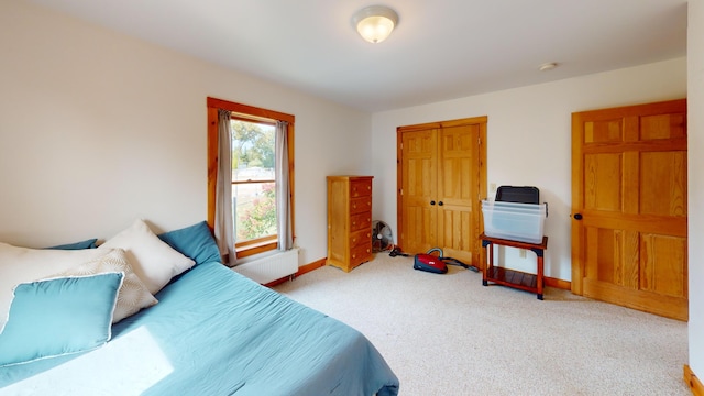 bedroom with a closet, radiator, and carpet floors