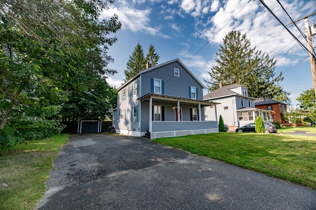 view of front of property with a front yard, a storage shed, and a porch