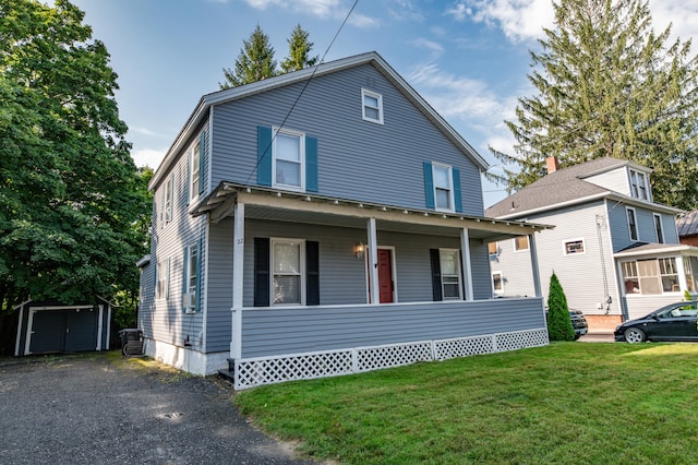 view of front of home with a front yard, a porch, and an outbuilding