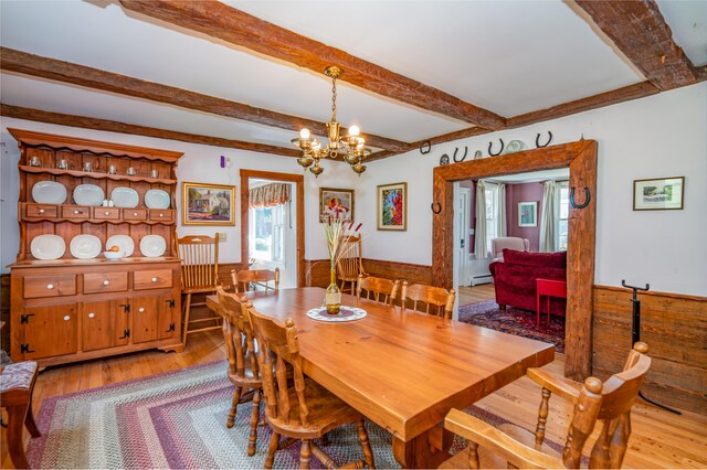 dining room featuring an inviting chandelier, light hardwood / wood-style floors, beamed ceiling, and a baseboard heating unit