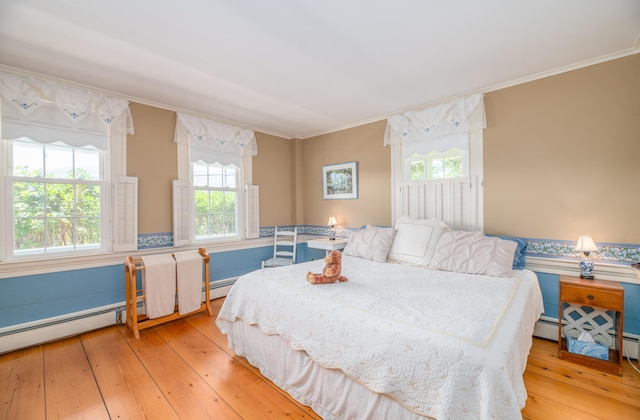 bedroom with a baseboard radiator, light wood-type flooring, and ornamental molding