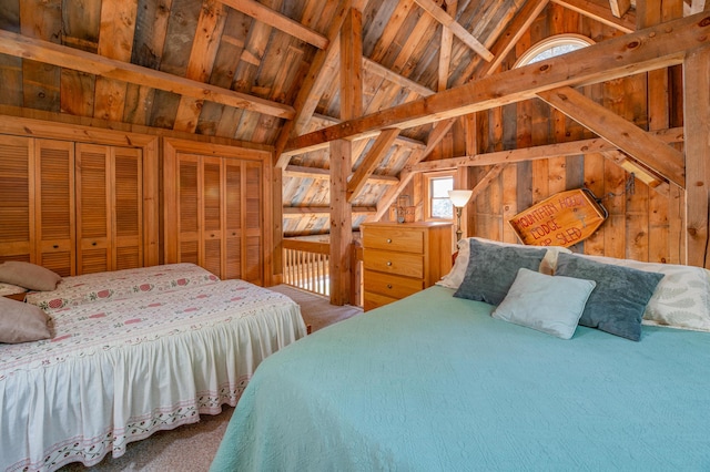 bedroom with two closets, lofted ceiling with beams, wood walls, carpet flooring, and wood ceiling