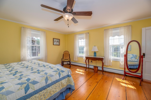 bedroom featuring a baseboard radiator, multiple windows, light wood-type flooring, and ornamental molding