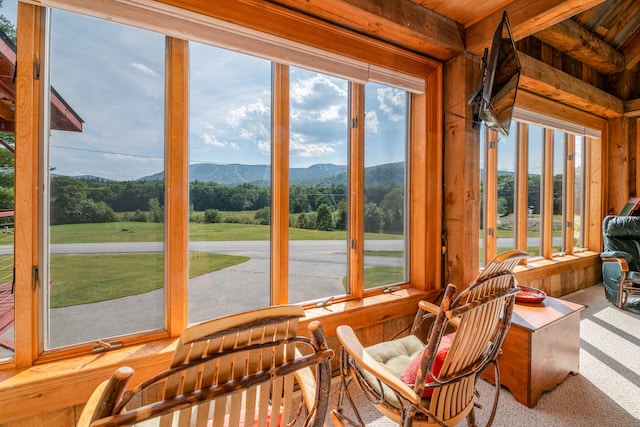 sunroom / solarium featuring wood ceiling, beam ceiling, and a healthy amount of sunlight