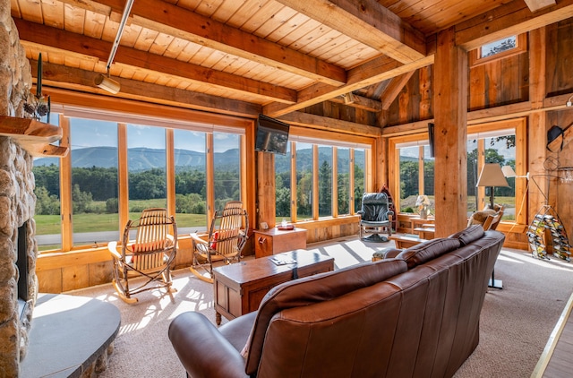 carpeted living area with lofted ceiling with beams, wooden walls, and wood ceiling