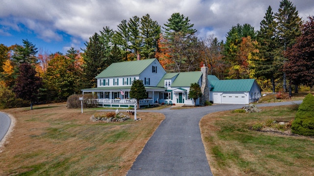 country-style home with a porch, metal roof, a front lawn, a chimney, and driveway