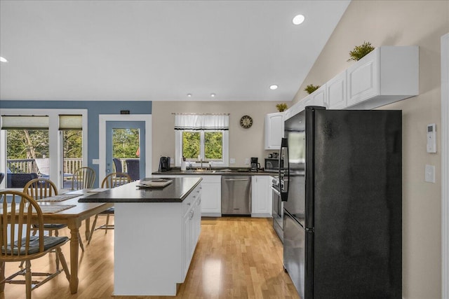 kitchen with a kitchen island, vaulted ceiling, light hardwood / wood-style floors, stainless steel appliances, and white cabinets