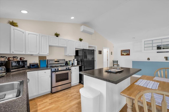 kitchen featuring light wood-type flooring, vaulted ceiling, a center island, appliances with stainless steel finishes, and white cabinets