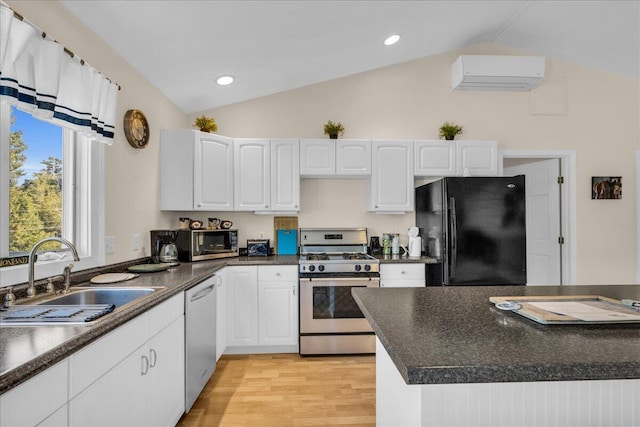 kitchen with a wall unit AC, sink, appliances with stainless steel finishes, lofted ceiling, and white cabinets