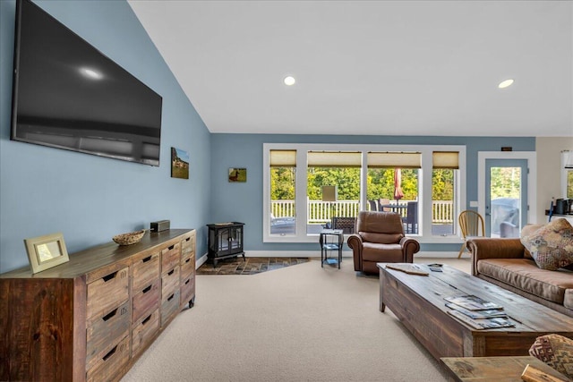 carpeted living room featuring vaulted ceiling and a wood stove