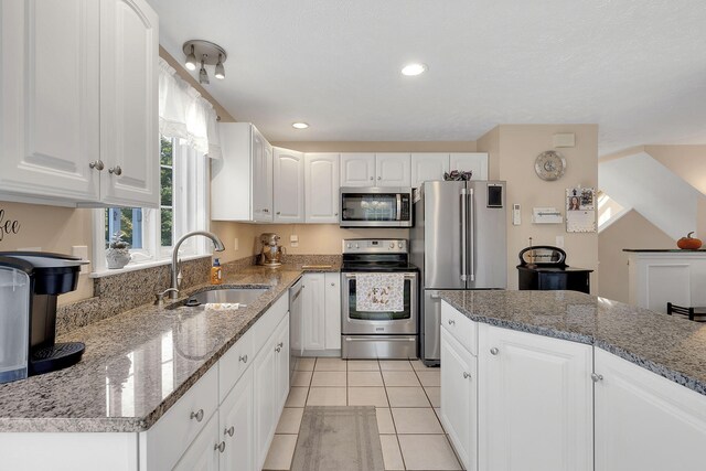 kitchen featuring light stone countertops, stainless steel appliances, sink, and white cabinetry