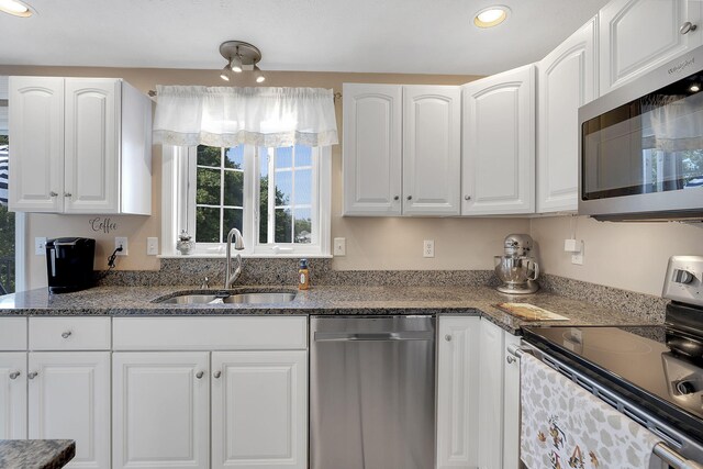 kitchen with dark stone countertops, white cabinetry, sink, and stainless steel appliances