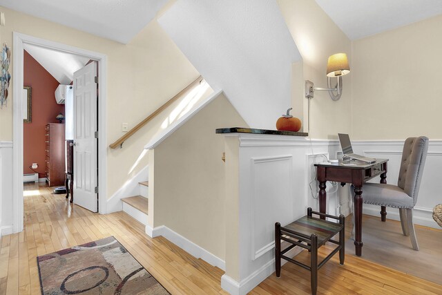 office space featuring vaulted ceiling, light hardwood / wood-style floors, and baseboard heating