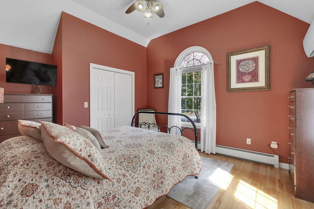 bedroom with lofted ceiling, a baseboard heating unit, ceiling fan, and light hardwood / wood-style flooring