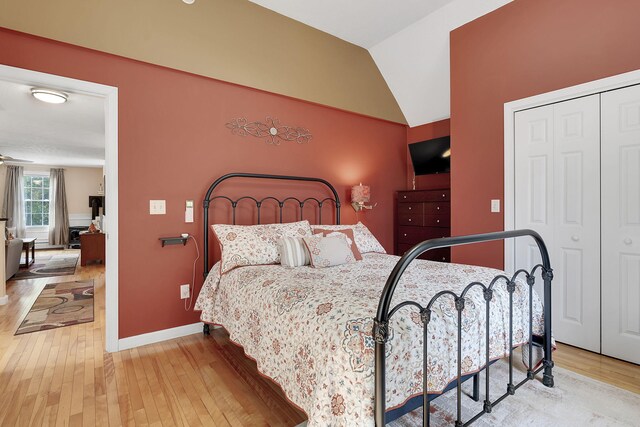 bedroom with light wood-type flooring, a closet, and lofted ceiling