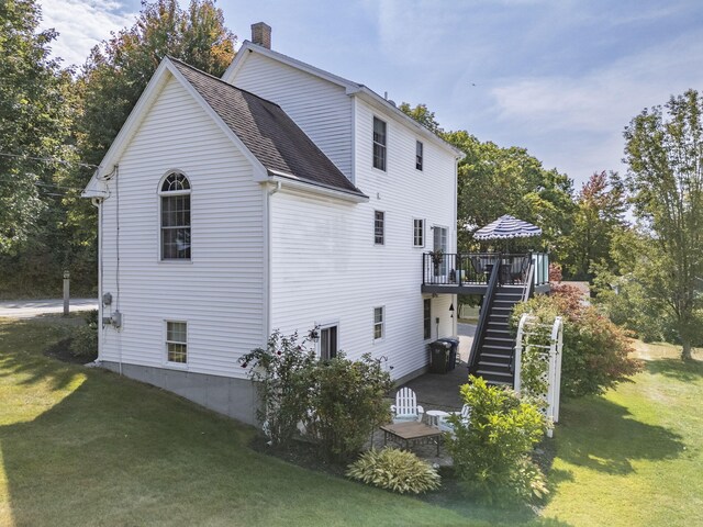 view of side of property with a yard and a wooden deck