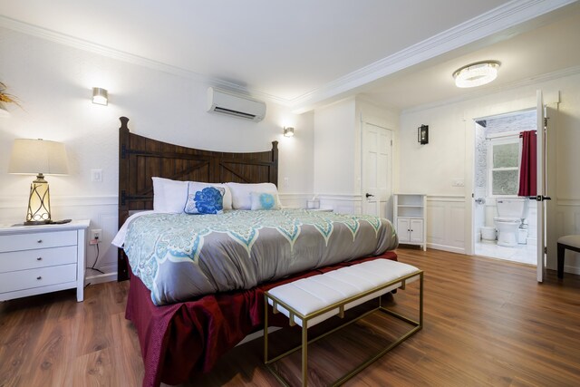 bedroom featuring crown molding, a wall mounted AC, ensuite bath, and dark hardwood / wood-style floors