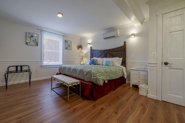 bedroom with a wall mounted AC, hardwood / wood-style flooring, and ornamental molding