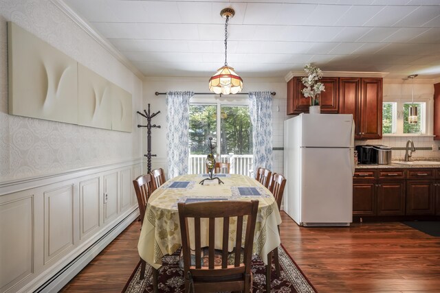 dining area with dark wood-type flooring, a baseboard radiator, plenty of natural light, and sink