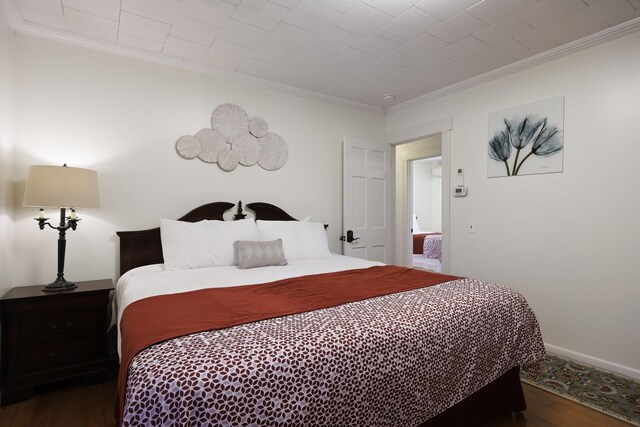 bedroom with dark hardwood / wood-style flooring and crown molding