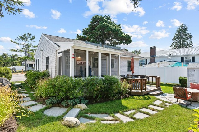 rear view of property featuring a sunroom, a yard, and a deck