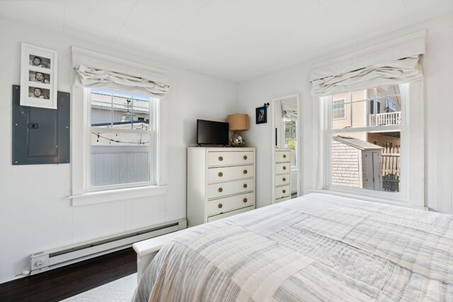 bedroom featuring hardwood / wood-style floors, electric panel, and baseboard heating