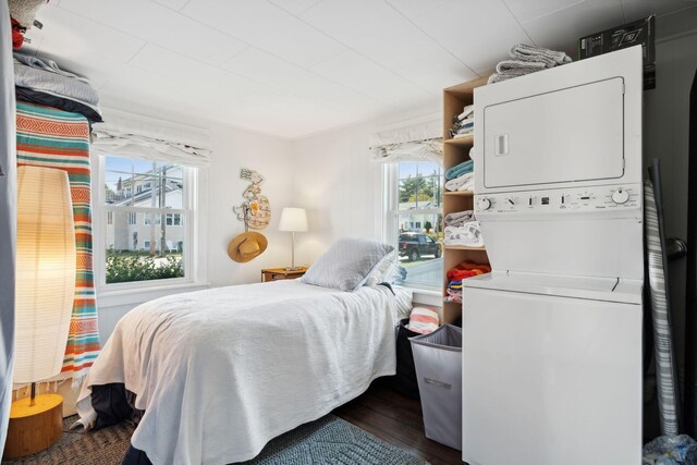 bedroom featuring stacked washer / dryer and dark wood-type flooring