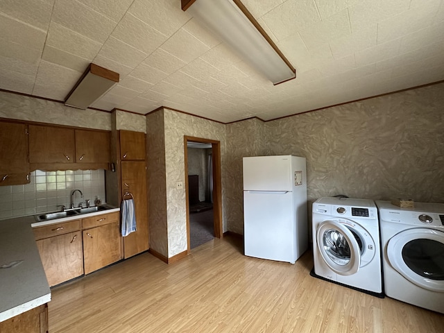 laundry room featuring light wood-type flooring, sink, and washing machine and clothes dryer